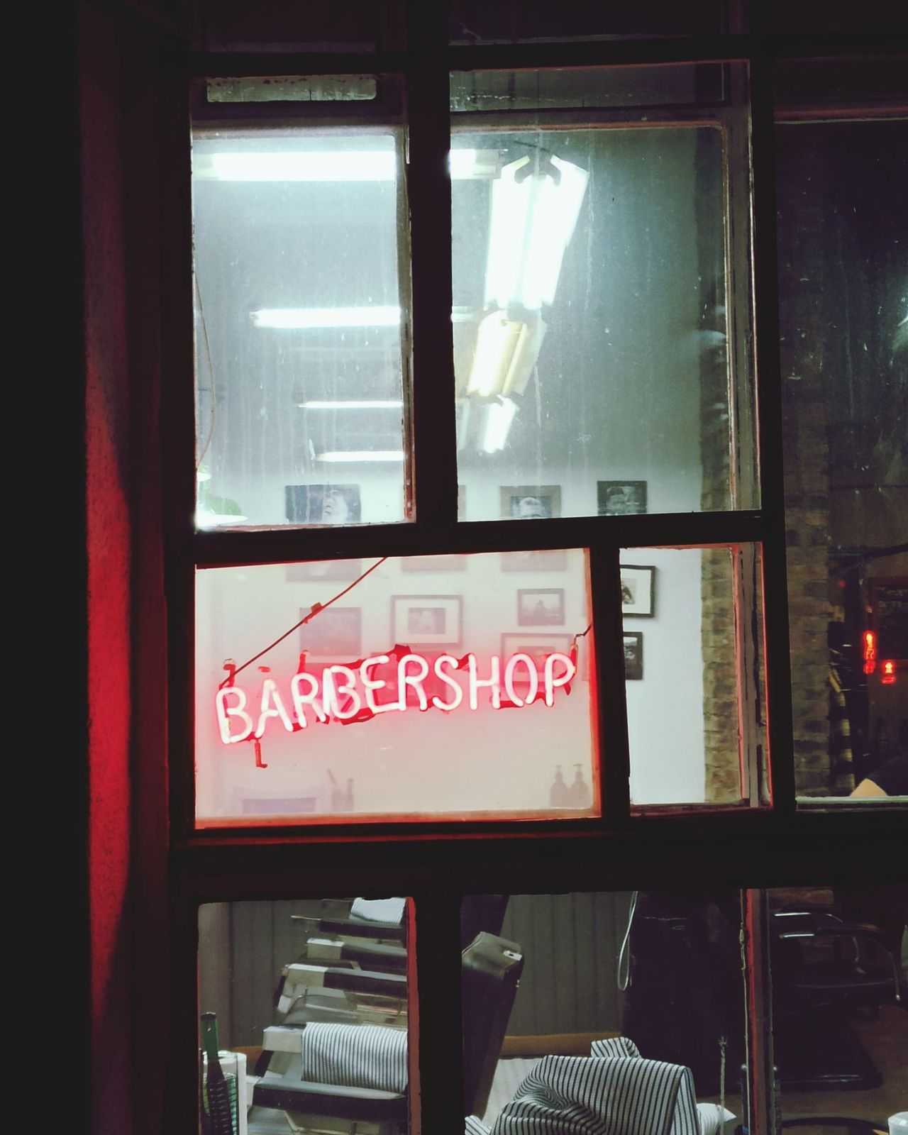 Letreiro de barbearia aceso na vitrine à noite